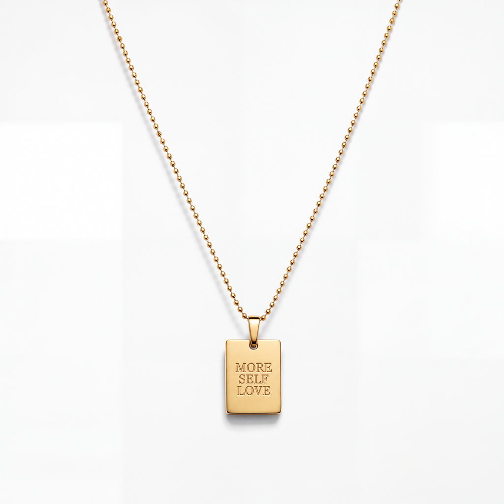 A gold ball-chain necklace with a rectangular gold pendant engraved with the words 'MORE SELF LOVE' in all caps, shown against a clean white background.