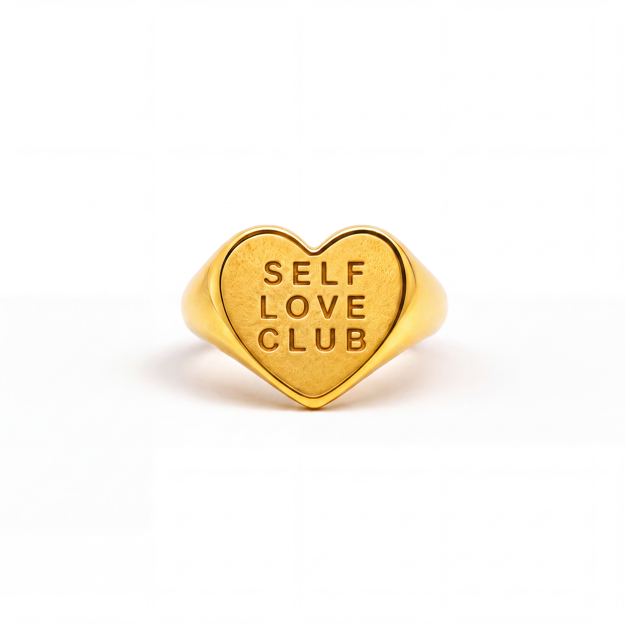 A gold heart-shaped signet ring engraved with the words 'SELF LOVE CLUB' in a warm yellow-gold finish, centered on a clean white background.