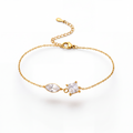 A delicate gold chain bracelet featuring a marquise-cut clear gemstone and a small triangular clear gemstone set in gold, displayed on a clean white background.