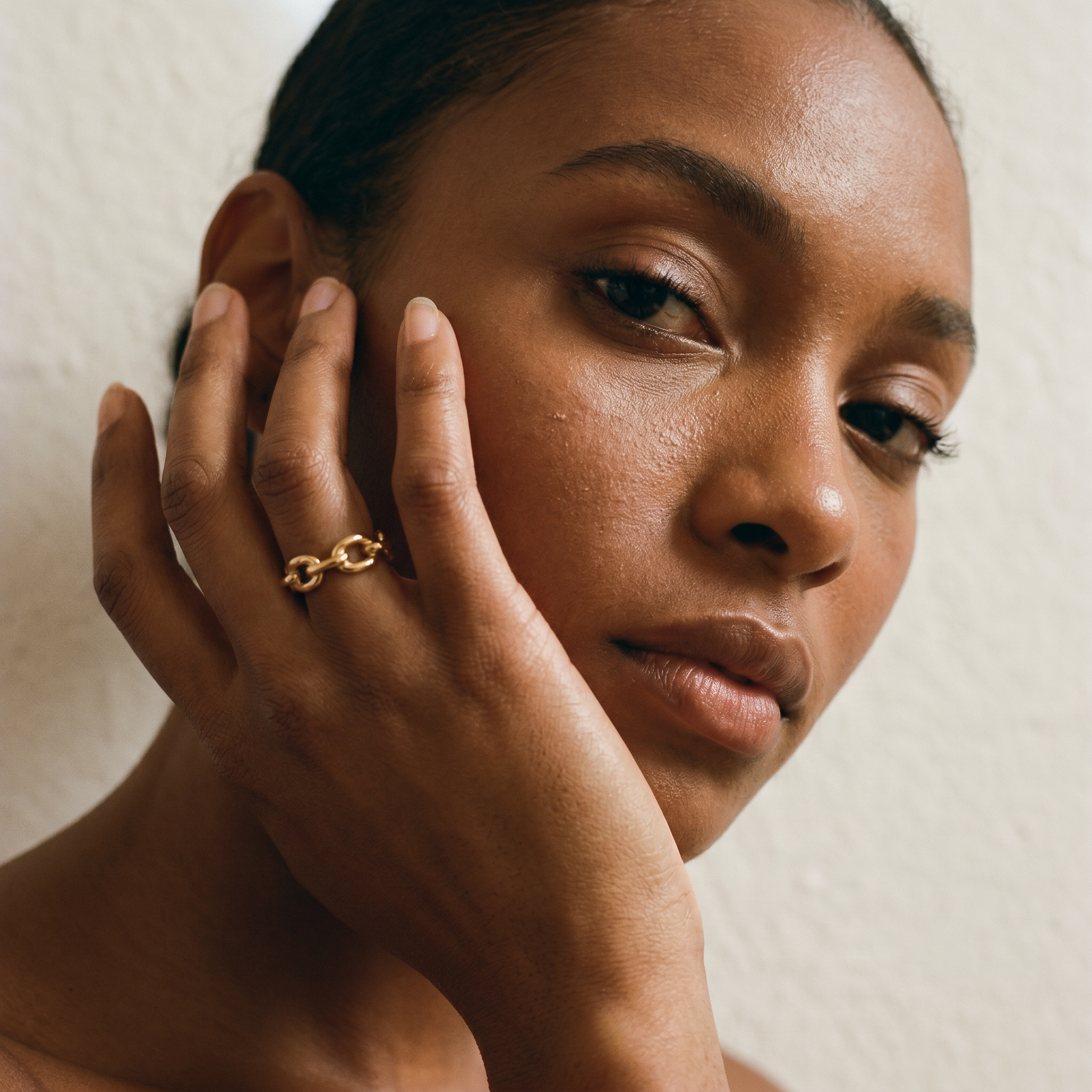 Woman wearing a gold ring on her finger with a neutral background