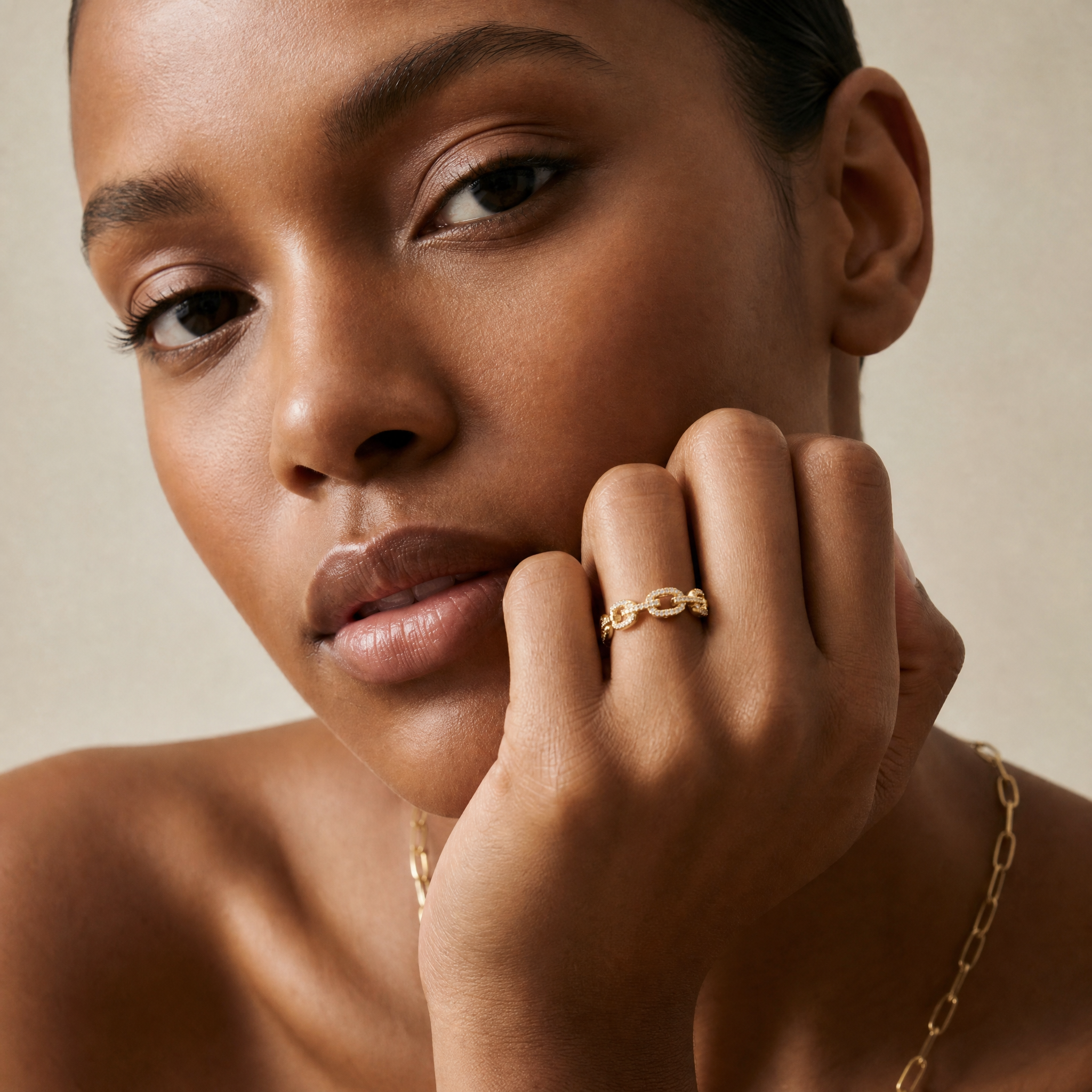 Woman wearing gold jewelry with a neutral background