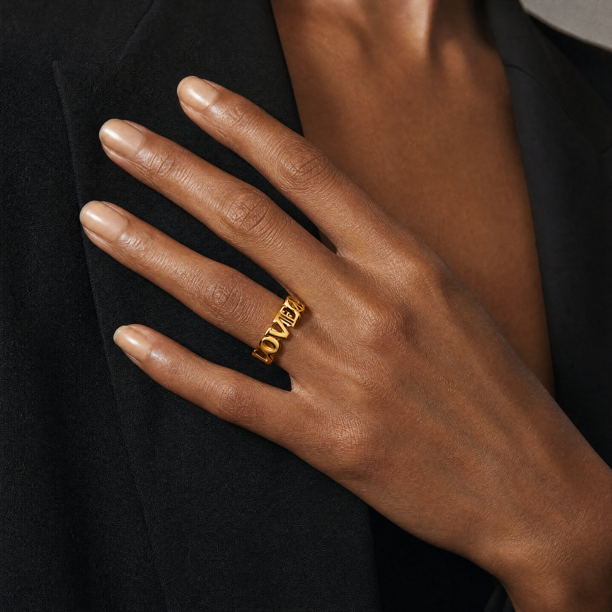 Hand wearing a gold ring with a blurred background